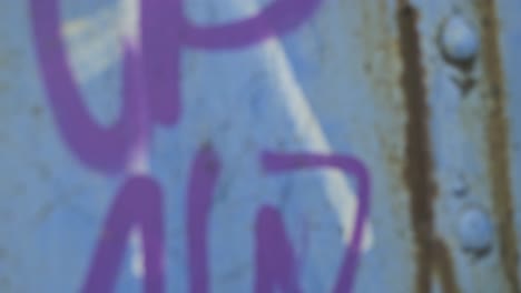 young-hipster-male-in-black-jacket-spinning-around-while-dancing-near-abandoned-industrial-crane-with-graffiti-on-urban-waterfront