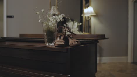 Slow-Motion-of-Female-Wedding-Shoes-Inside-on-a-Table-Beside-a-Vase-of-Flowers