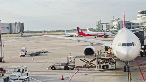 Airplane-in-The-Airport-Taxing-and-Transporter-Load-the-Luggage-In-The-Afternoon-in-Düsseldorf-Airport