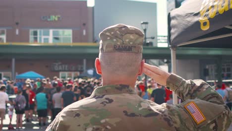 Uniformierter-Soldat-Grüßt-Während-Der-Nationalhymne-Die-Amerikanische-Flagge-Vor-Der-Menge