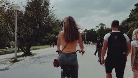 A-woman-rides-a-bike-in-slow-motion-through-a-park-in-Amsterdam,-Netherlands