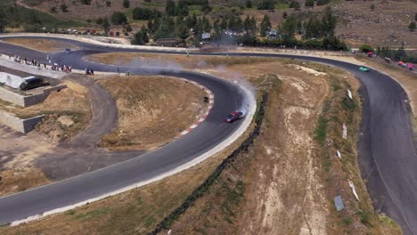 Toma-Aérea-De-Seguimiento-De-Un-Auto-De-Carreras-A-La-Deriva-En-Una-Esquina-En-La-Pista-De-Carreras---Imágenes-De-Drones-FPV