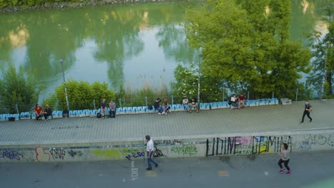 Paisaje-Ribereño-Con-Gente-Paseando-Y-Relajándose-En-La-Orilla-Del-Río-Danubio,-Viena