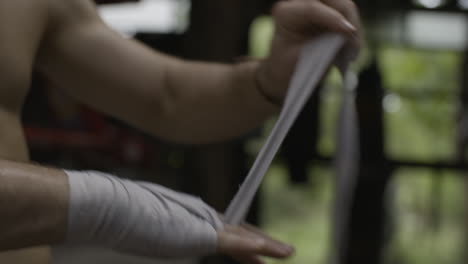 Boxer-wrapping-his-right-hand-with-white-bandage,-slow-motion