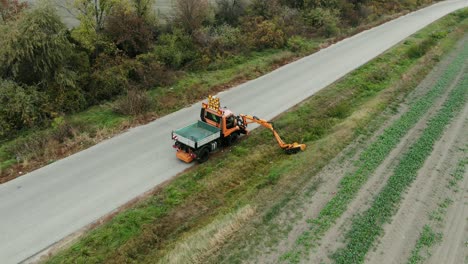 Mower-cutting-the-grass-on-the-road-shoulder-with-verge-mowing-arm