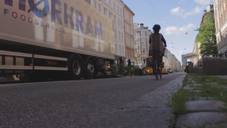 Cars-and-bikes-crossing-the-street-in-the-city-center,-passing-alongside-the-sidewalk