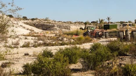 Tractor-John-Deere-Remolcando-Equipos-De-Movimiento-De-Tierras-Amarillas-En-Un-Sitio-De-Construcción-Cerca-De-Torrevieja,-España