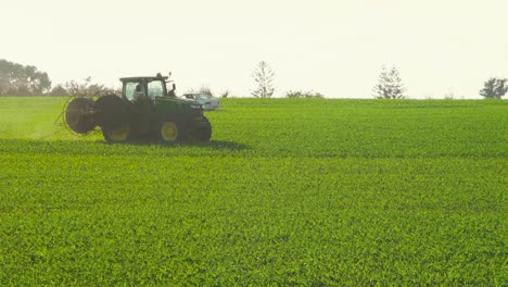 El-Tractor-John-Deere-Coloca-Gotas-De-Plástico-En-Un-Campo-De-Maíz,-Campo-De-Maíz-Verde-En-Cámara-Lenta