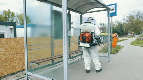 A-man-in-protective-equipment-disinfects-bus-stop