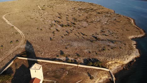 Drone-approaching-church-tower-on-the-island-Zecevo-near-Zadar,-Croatia-in-sunset