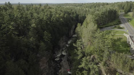 Drone-shot-of-water-going-through-a-canyon,-moving-forward-and-tilting-the-camera-down