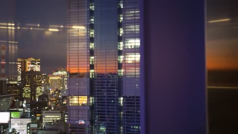 Reflexiones-De-Puesta-De-Sol-Muy-Interesantes-En-Edificios-De-Tokio-Con-Ascensores-En-Movimiento,-Cardán,-Toma-En-Movimiento-Panorámica-Hacia-La-Izquierda,-Reflejos-De-Ventana-Y-Enfoque-Selectivo