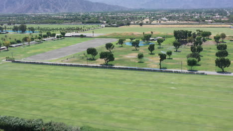 Vuelo-Panorámico-Hacia-Atrás-Sobre-La-Hierba-Verde-Con-Vistas-Al-Colorido-Edificio-De-La-Torre-Redonda-En-Llanuras-Tropicales-Occidentales-Planas-Con-Cordillera-En-El-Fondo