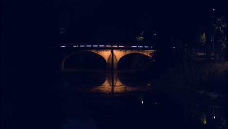 The-stunning-view-of-a-small-bridge-in-Leiria,-Portugal-with-lights-on-the-sides-of-the-arch-over-the-Rio-Lis-River---Wide-shot