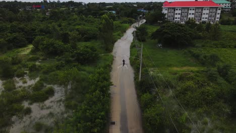 Aerial-footage-of-biking-along-a-flooded-street-in-a-village-of-Thailand-after-a-pouring-of-rain