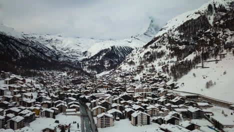 Drone-shot-over-the-town-of-Zermatt,-Switzerland-covered-in-snow-with-the-Matterhorn-mountain-behind