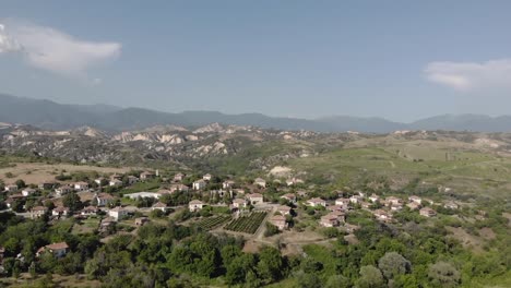 Fliegen-In-Richtung-Eines-Kleinen-Dorfes-In-Den-Bergen,-Umgeben-Von-Bäumen