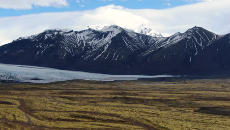 Vista-Sobre-El-Glacer-Islandés-Con-Hermosas-Vistas-Perfectas-A-La-Montaña-Con-Nieve-En-Las-Cimas-Y-Gras-Dorado