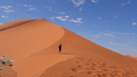 Man-descends-dune-walking-alone-in-Namib-Naukluft-National-Park,-Namibia