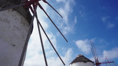 Looking-along-the-famous-windmills-by-the-beach-in-Mykonos-with-tourists-walking-up-to-them-from-the-sand