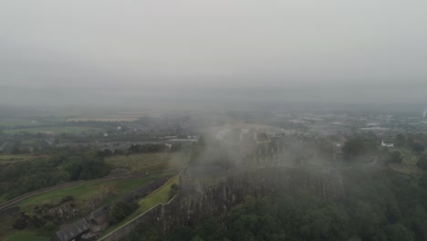 Toma-Orbital-Aérea-Amplia-Del-Castillo-De-Stirling-Con-Nubes-Bajas-Sobre-El-Castillo-Y-Los-árboles,-Mirando-Al-Norte-Sobre-El-Castillo.