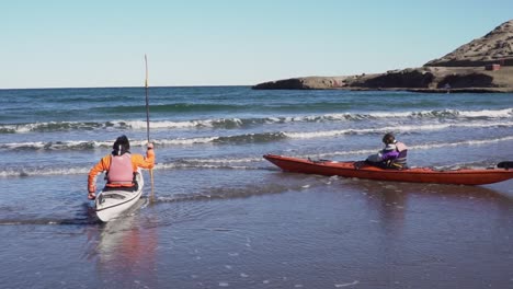 Two-people-riding-kayaks-on-the-coast-line-of-the-sea---Slowmotion