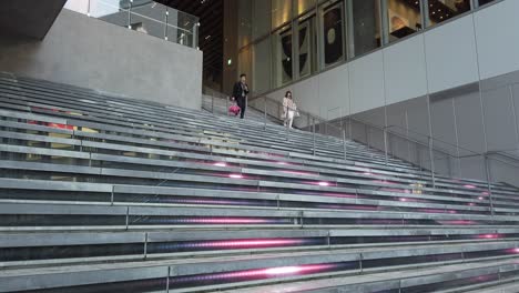 Ein-Mann-Und-Eine-Frau-Gehen-In-Shibuya,-Tokio,-LED-beleuchtete-Stufen-Hinunter