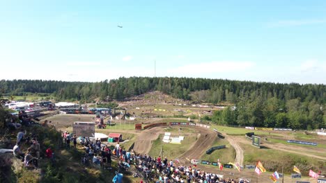 Panning-of-motocross-cup,-MXGP-of-Sweden,-audience-sitting-on-green-hill-with-view-over-motocross-circuit