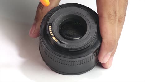 Pair-of-male-hands-cleaning-the-inside-of-50mm-canon-lens-using-a-blower