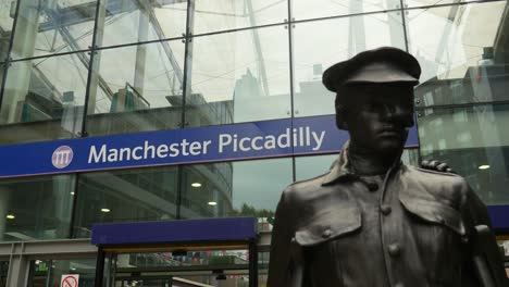 Schild-Am-Bahnhof-Manchester-Piccadilly-Vor-Dem-Bahnhof,-Bewölkter-Tag,-Beleuchtung,-Flacher,-Einfacher-Bahnhof,-öffentliches-Verkehrsgebäude,-Hauptbahnhof-Großbritannien-Mit-Denkmal-Im-Vordergrund,-4k-25p