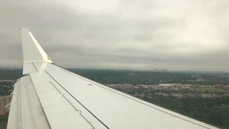 POV-airplane:-view-of-plane-wing,-flat-landscape-and-landing-at-airport,-handheld