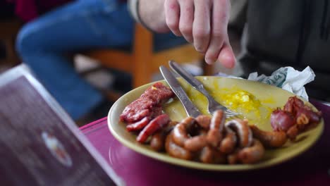 Pork-Sausage-and-Meat-platter-has-been-served-in-a-restaurant-in-a-yellow-plate-with-knife-and-a-fork