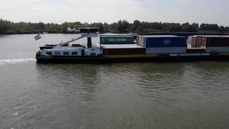 Niederländisches-Binnenschiff-Mit-Containern-Beladen,-Das-Auf-Einem-Niederländischen-Fluss-Segelt