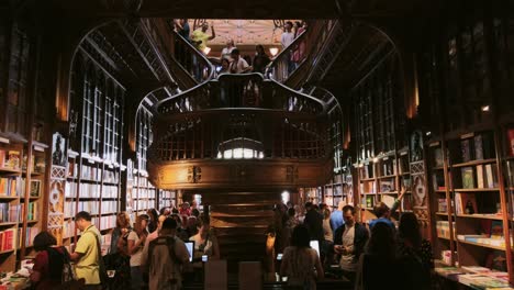 People-explore-staircase-and-bookshelves-inside-crowded-Livraria-Lello-in-Porto,-Portugal