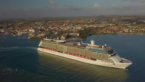 Vista-Aérea-De-Un-Gran-Crucero-Que-Sale-Del-Muelle-En-Un-Día-Soleado-Con-Un-Lento-Deslizamiento-Hacia-Atrás-4k