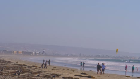 People-enjoying-Kite-Surfing-and-other-activities-at-Silver-Strand-State-Beach-on-a-hazy-day,-Locked-establishing-shot