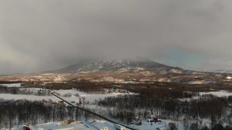 4K-drone-footage-of-Niseko-volcano-in-Japan-during-winter-with-snowy-mountains-and-trees-during-sunset-and-golden-hour