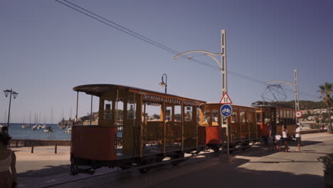 Alte-Orangefarbene-Vintage-Straßenbahn-In-Soller,-Die-Durch-Die-Stadt-Fährt,-Mit-Passagieren,-Die-Entlang-Laufen