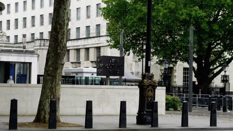 Red-double-decker-bus-passes-New-Scotland-Yard-sign-of-the-Met-,-London,-UK-4K60p