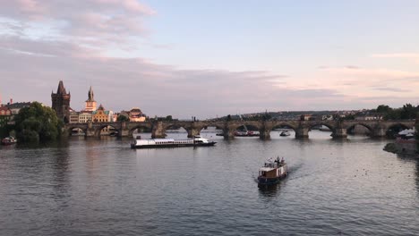 Boats-sailing-in-the-Vltava-River-with-Charles-Bridge-at-the-background-during-the-Sunset-on-a-Summer-day-in-Prague