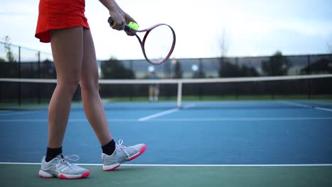 Una-Mujer-Con-Ropa-Deportiva-Jugando-Tenis-Rebotando-Una-Pelota-Preparándose-Para-Servir