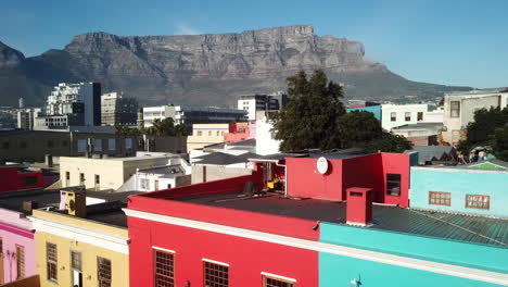 Toma-Aérea-De-Drones-De-Bokaap-Wale-Street-Y-Punto-Verde-Entre-Strand-Street-Y-Rose-Street-En-Ciudad-Del-Cabo,-Sudáfrica-En-Un-Soleado-Día-De-Cielo-Azul