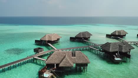 Aerial,-drone-shot,-over-villas-on-turquoise-sea,-at-a-lagoon,-on-a-sunny-day,-on-the-Conrad-Rangali-island,-in-Maldives