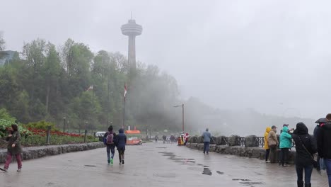 Panoramic-view-of-the-Skylon-Tower-on-a-rainy-day-as-people-pass-by,-Wide-Angle