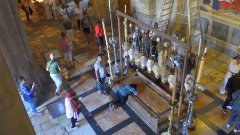 People-kneeling-in-front-of-stone-of-anointing-in-the-Church-of-the-Holy-Sepulchre,-Jerusalem,-Israel