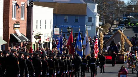 Close-up-of-flags-zooming-out-to-a-large-crowd-of-military-members-and-army-generals-marching-down-the-street-during-the-Thanksgiving-Parade-2019-in-Plymouth-Massachussetts