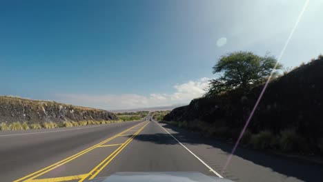 Driving-on-the-road-through-dry-grass-and-bush-landscape-in-Hamakua-District-of-Hawaii,-dash-cam-pov