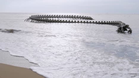 Olas-Rompiendo-En-La-Playa,-Inclinadas-Hacia-Arriba-Revelan-La-Obra-De-Arte-&quot;serpiente-De-Océano&quot;