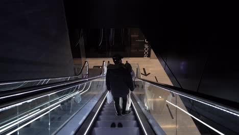 Going-down-an-escalator-in-Canary-Wharf,-subway,-London,-England,-wide-shot