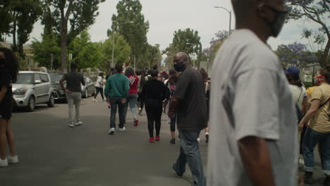 Group-of-protestors-marching-down-the-middle-of-the-street-during-a-protest-on-a-sunny-day